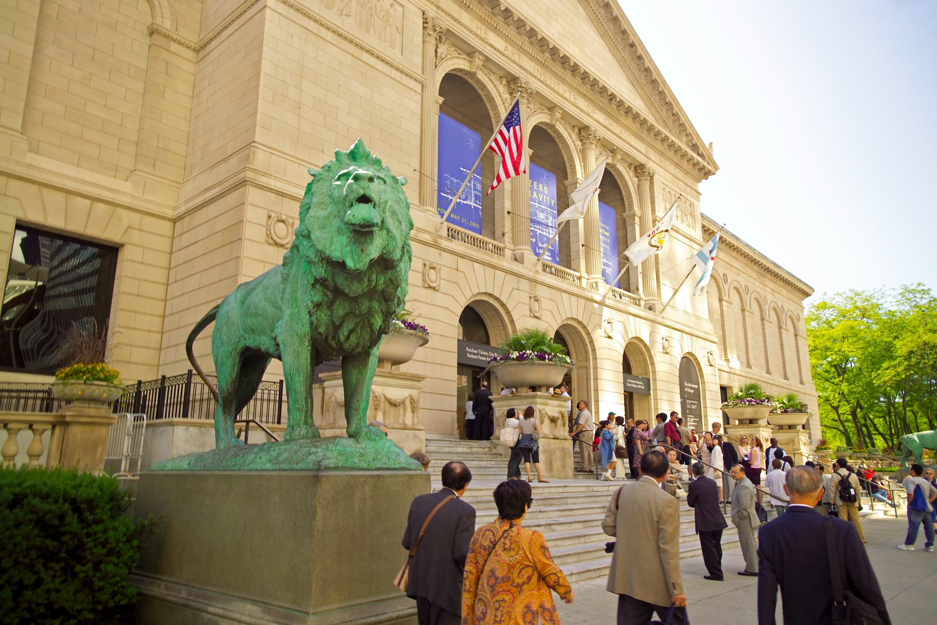 Visitors gather in front of an iconic cultural institution in Illinois, where a majestic bronze lion statue stands guard.