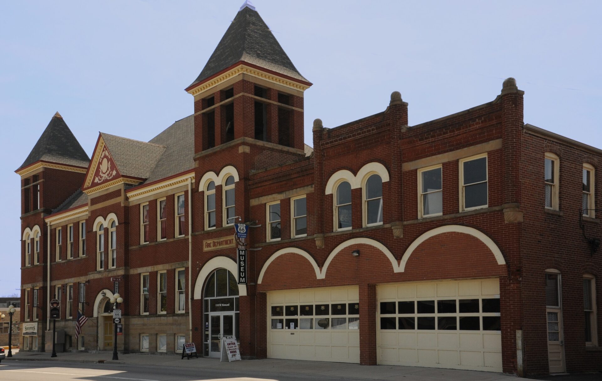 Red brick vintage fire station building in Illinois with arched doors and a classic tower under a clear sky.