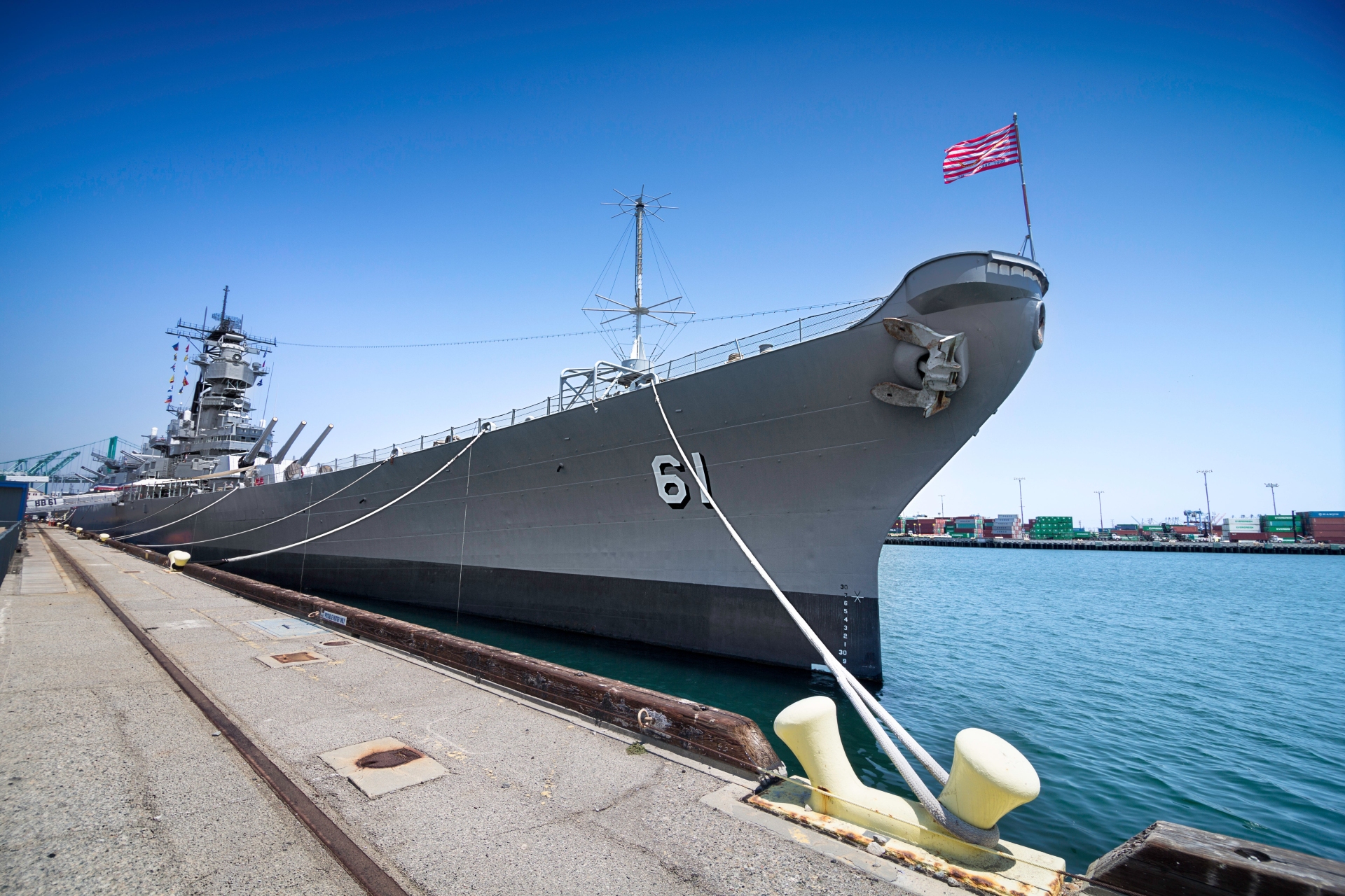 The proud bow of the USS Iowa, a retired battleship, flying the American flag as it rests docked in Los Angeles as a maritime museum.