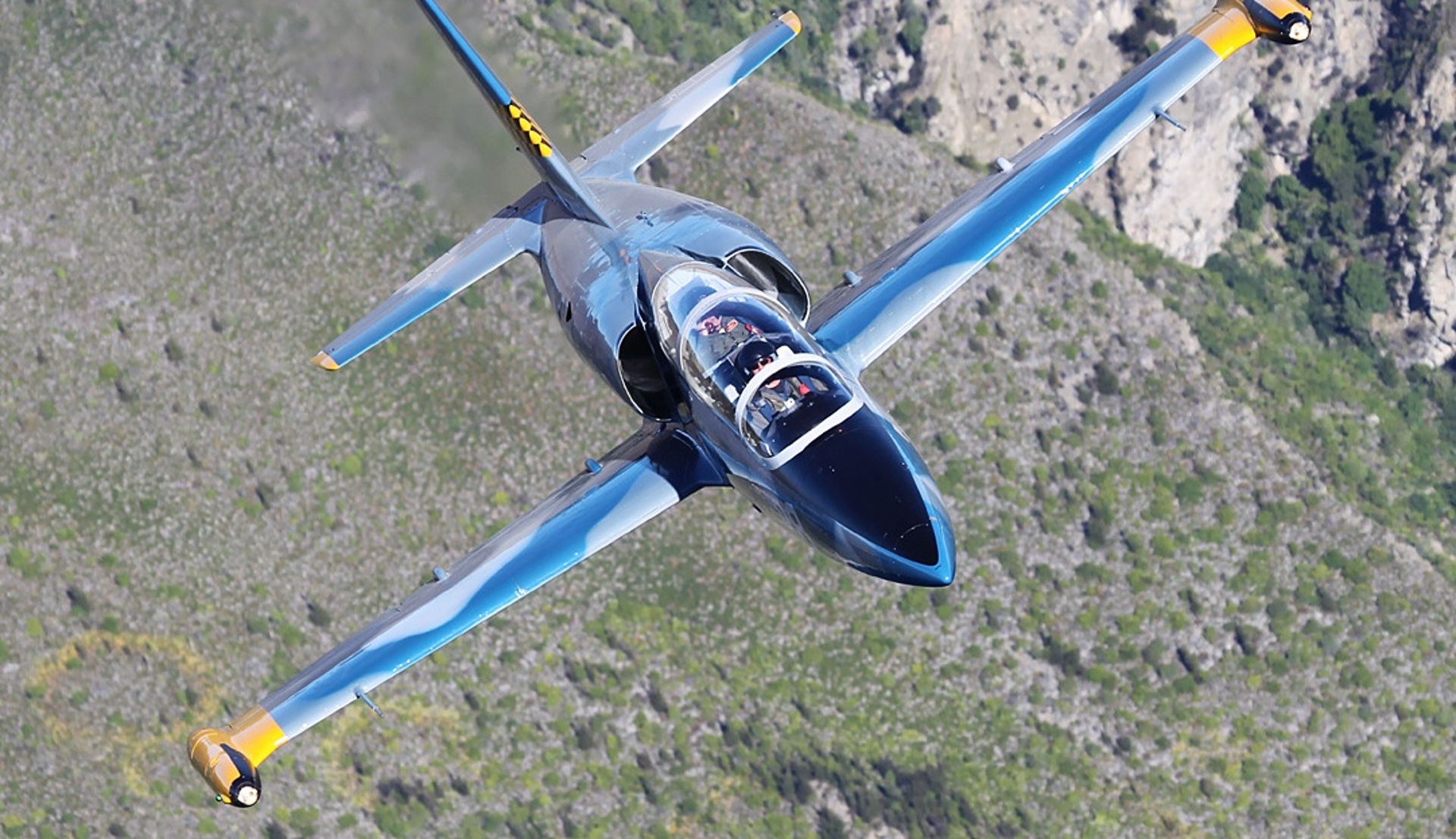 A sleek jet performing an impressive banking maneuver against the backdrop of Los Angeles's rugged landscape.