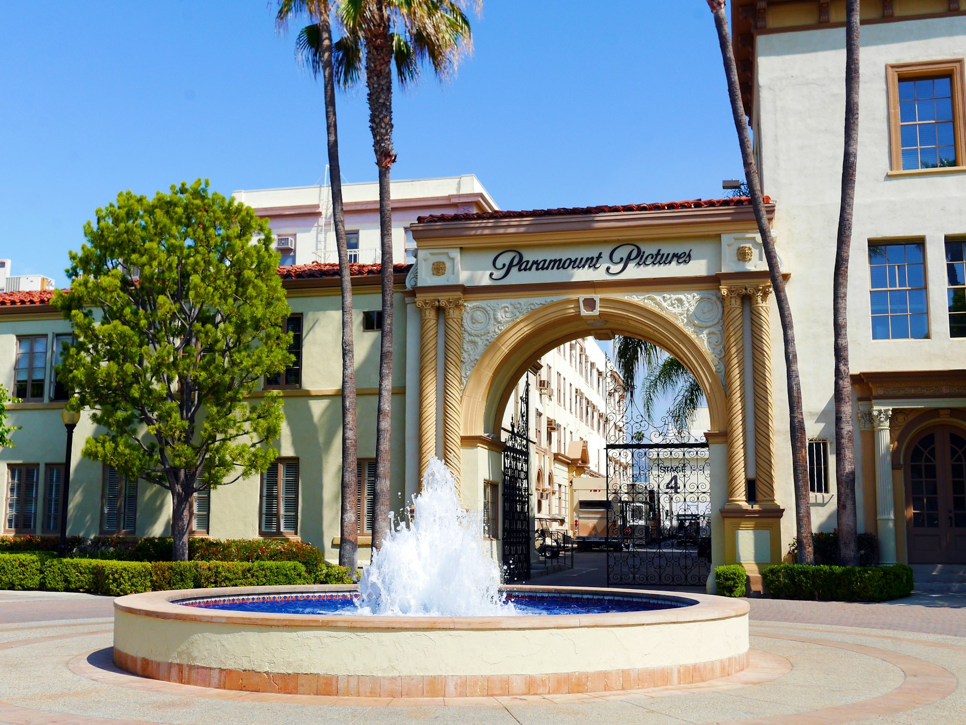A sunny day in Los Angeles at the iconic entrance of Paramount Pictures, with a fountain in the foreground adding a touch of tranquility to the scene.