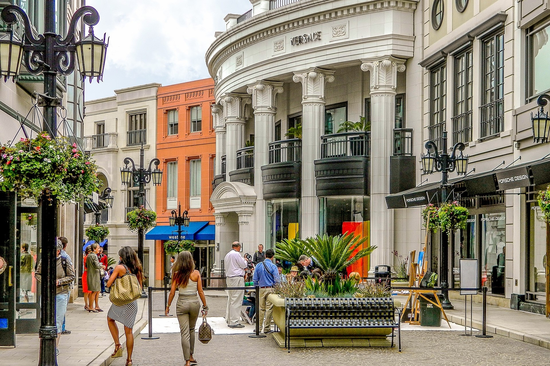 Shoppers stroll through an elegant outdoor shopping district in Los Angeles, featuring upscale storefronts and decorative street lamps, adding a touch of sophistication to a leisurely day out.