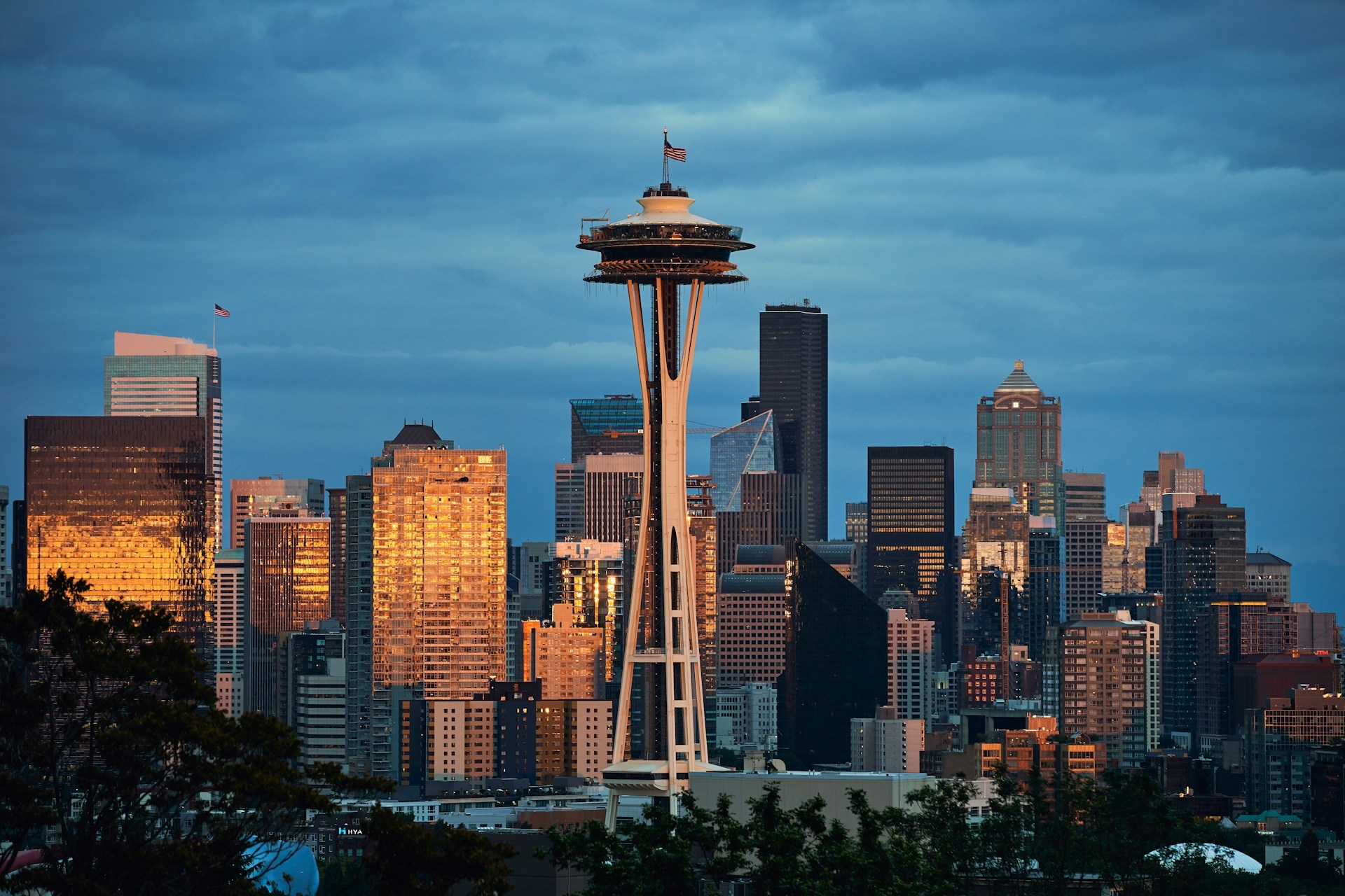 Seattle skyline at dusk with the iconic space needle standing prominently against the cityscape, illuminated by a warm glow as evening falls.