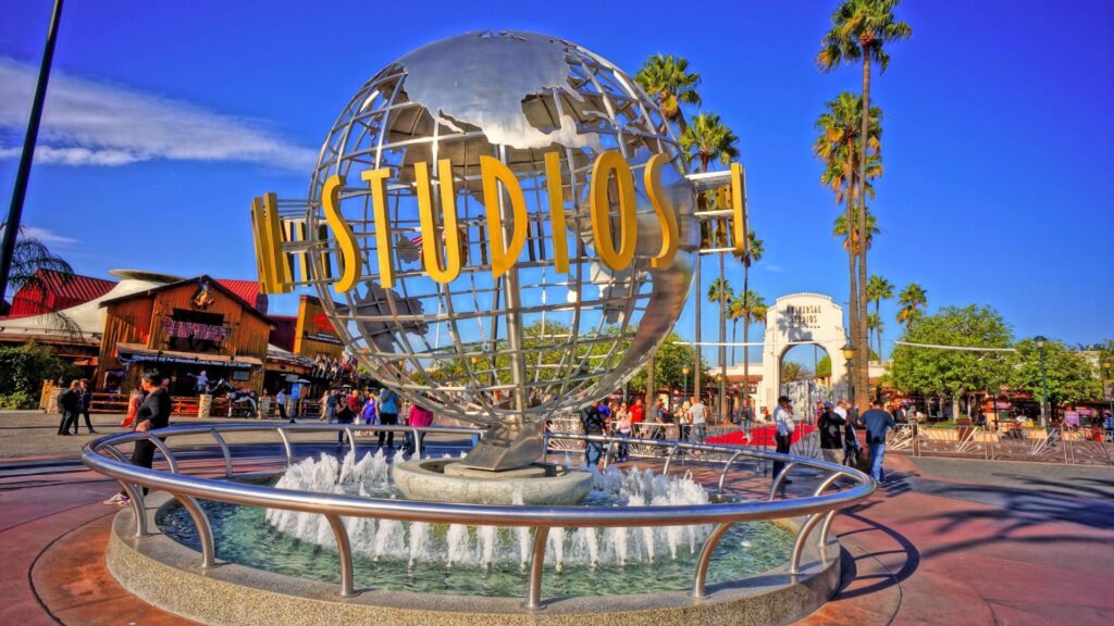 A vibrant day at Universal Studios in Los Angeles with the iconic rotating globe fountain greeting visitors under a clear blue sky.