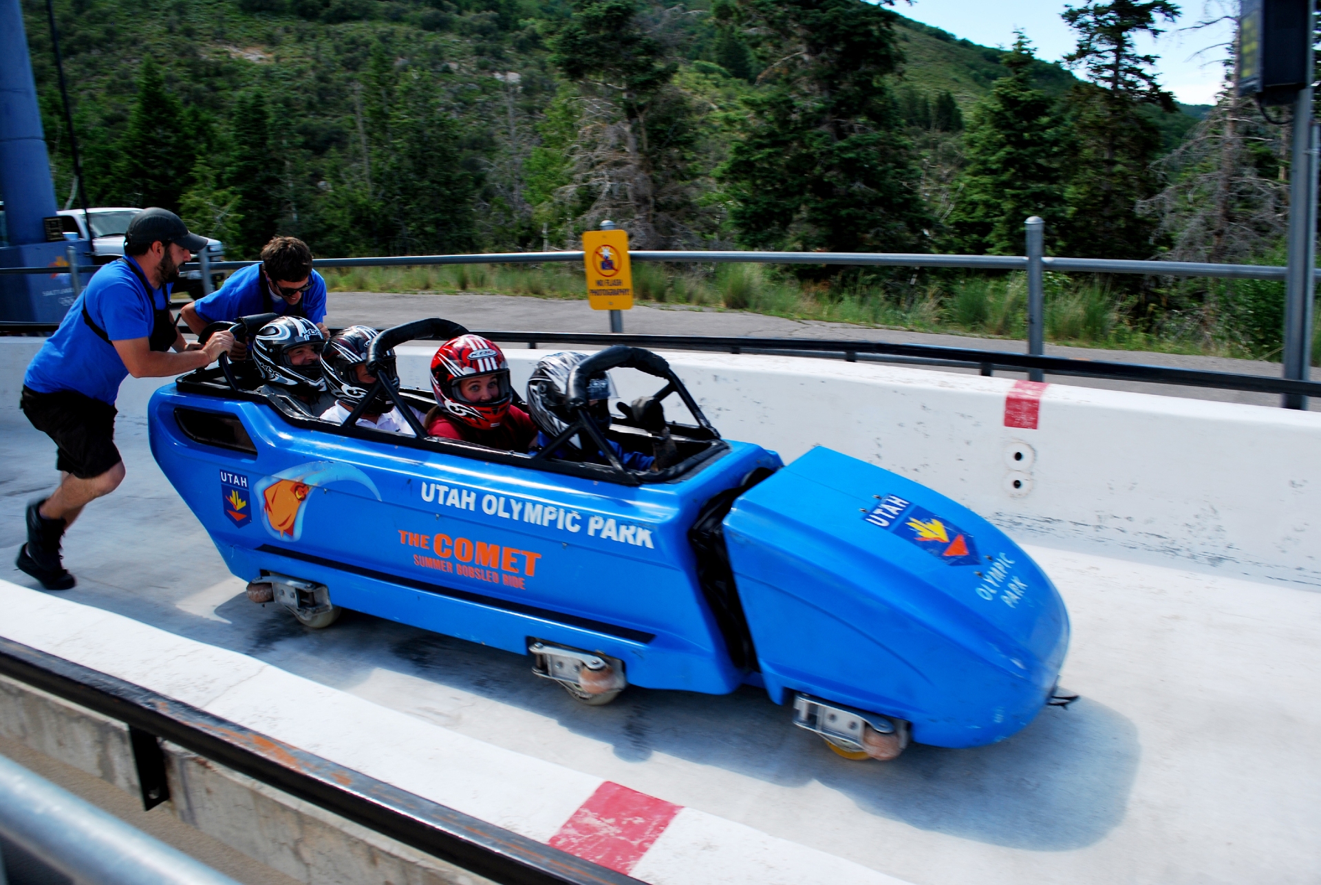 A thrilling bobsled experience at utah olympic park with an attendant assisting passengers as they prepare to zip down the track.