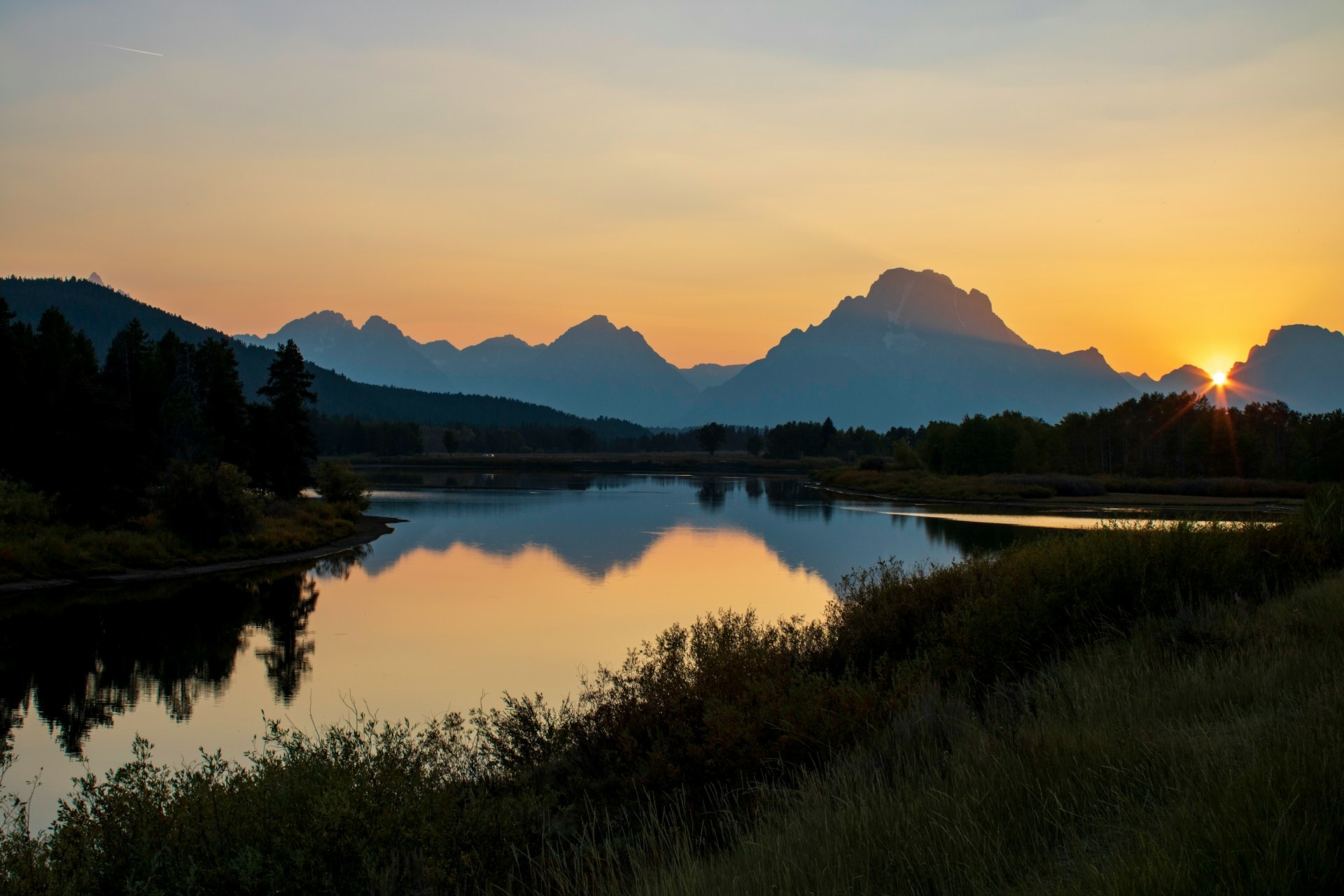 Jackson Wyoming beautiful sunset with the sun just going down behind the mountains with reflections in the lake