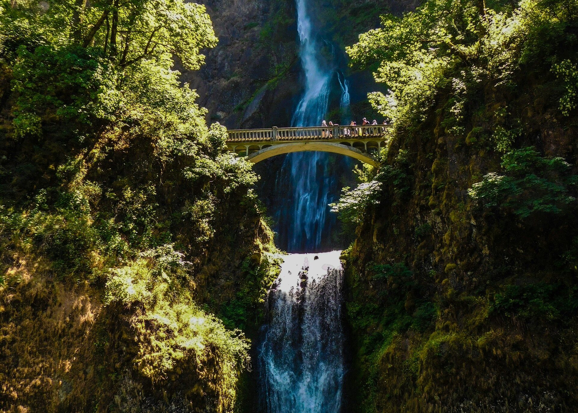 Multnomah Falls Oregon on a sunny day & people walking over the bridge