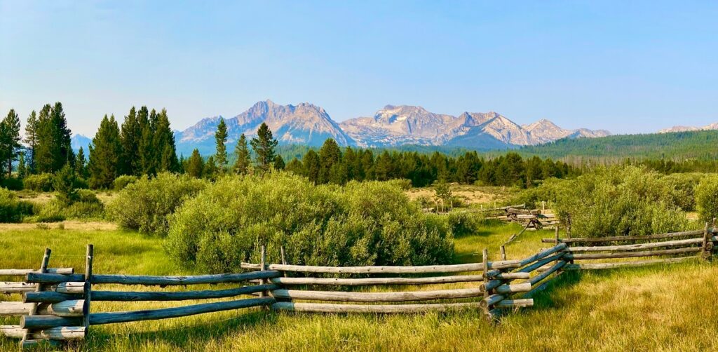 Sawtooth mountains Idaho with greenery & wooden fences
