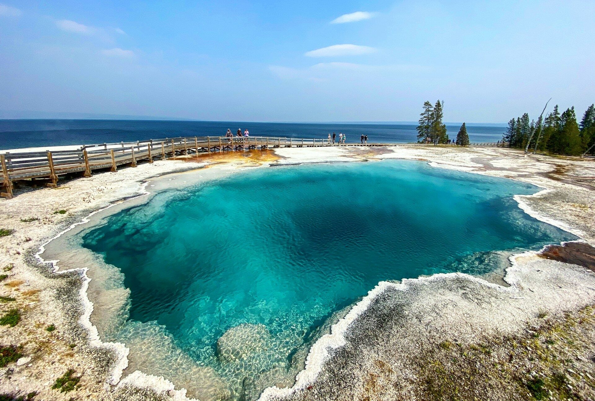 Yellowstone National Park thermal pool with the stunning blue colour of this clear water with tourists looking on