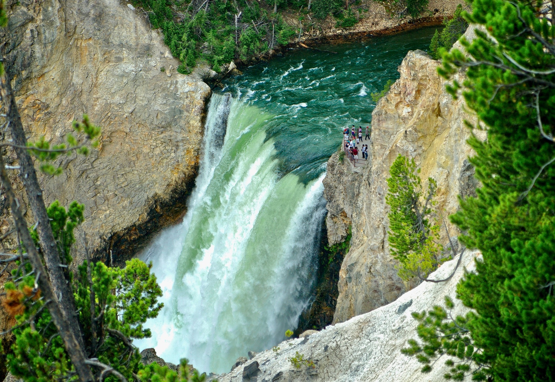 Yellowstone Waterfall Canyon Gorge show the sheer volume of water that goes over this waterfall with people looking on from the lookout platform