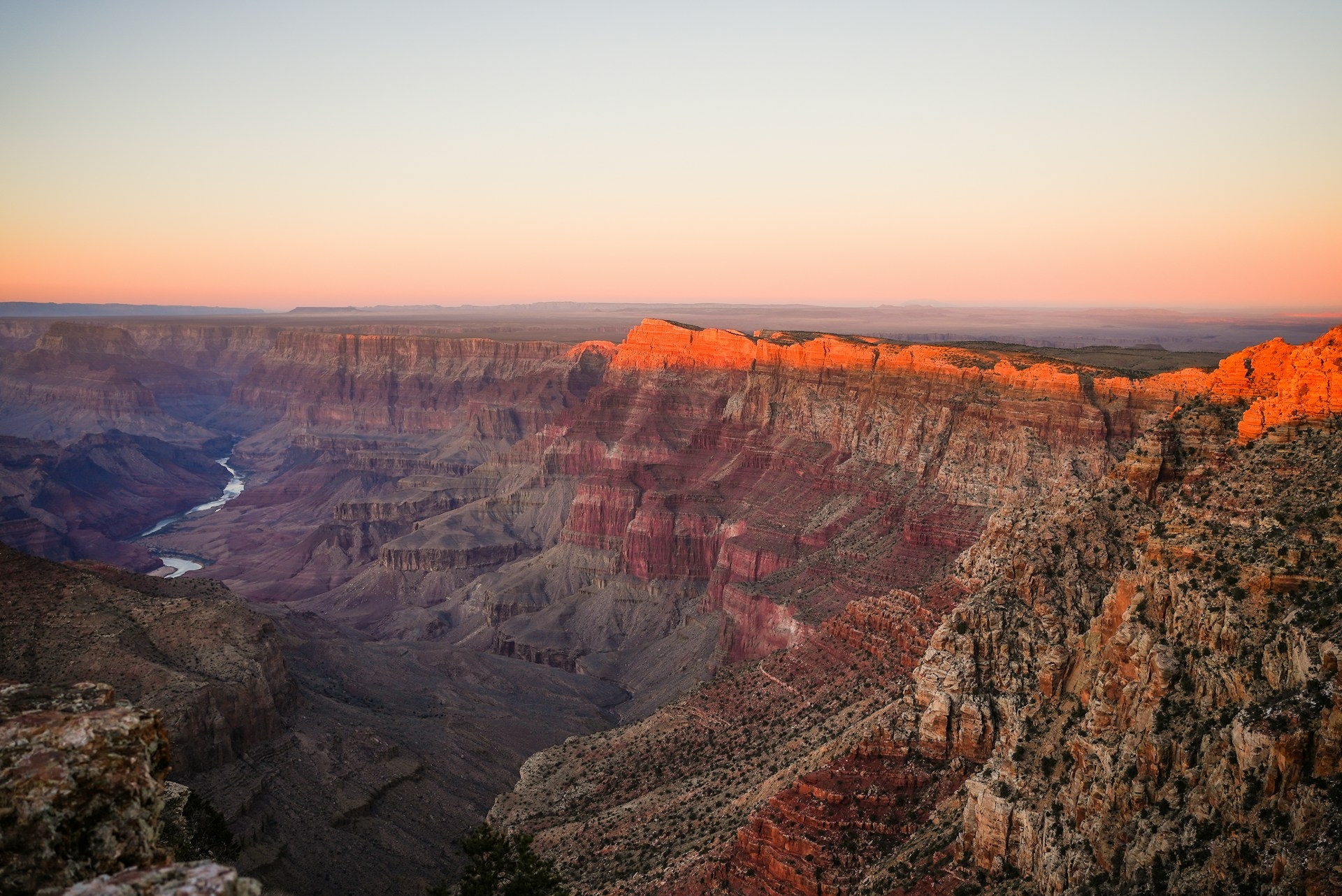 Grand Canyon sun catching the top of the canyon's rock formation with the river below