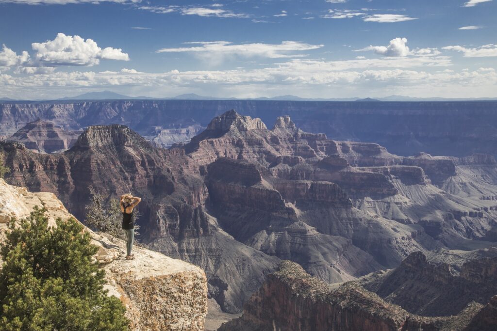 Grand Canyon with woman standing on the edge of the rock looking over the canyon