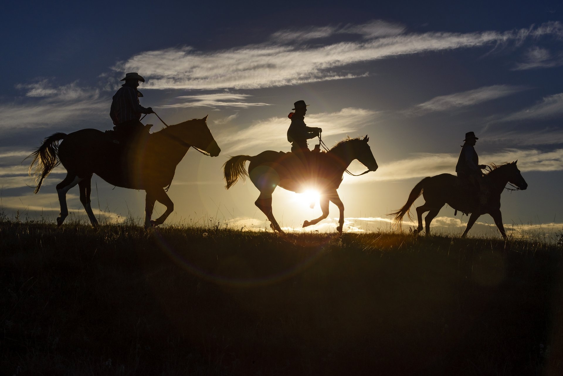 HorsebackRiding South Dakota at sunset with the silhouette of the horse & men
