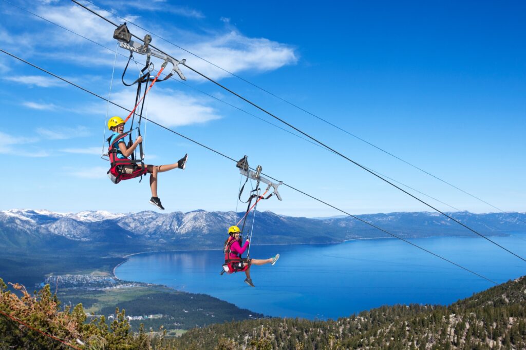 Two people zip lining with Lake Tahoe in the background Credit Heavenly Mountain