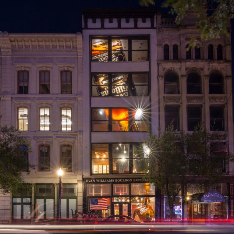 Evan Williams Bourbon Whiskey Row Cast Iron night downtown with a unique shop with a massive bottle in pouring bourbon into a glass