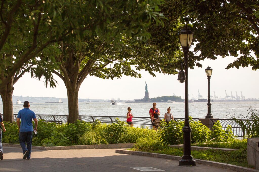 Lower Manhattan Battery Park showing the green trees in summer and the statue of liberty in the background