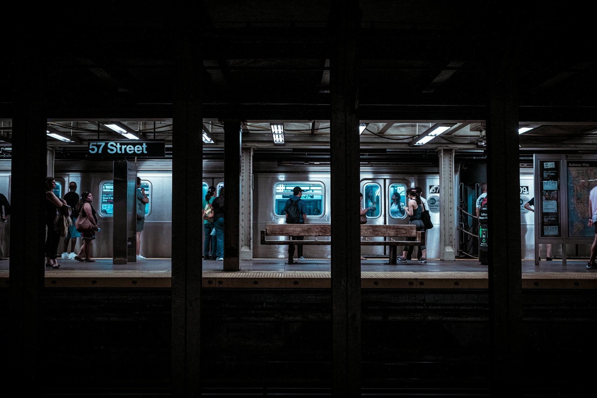 New York Subway Station underground with a train pulling up to a stop and people waiting to get on