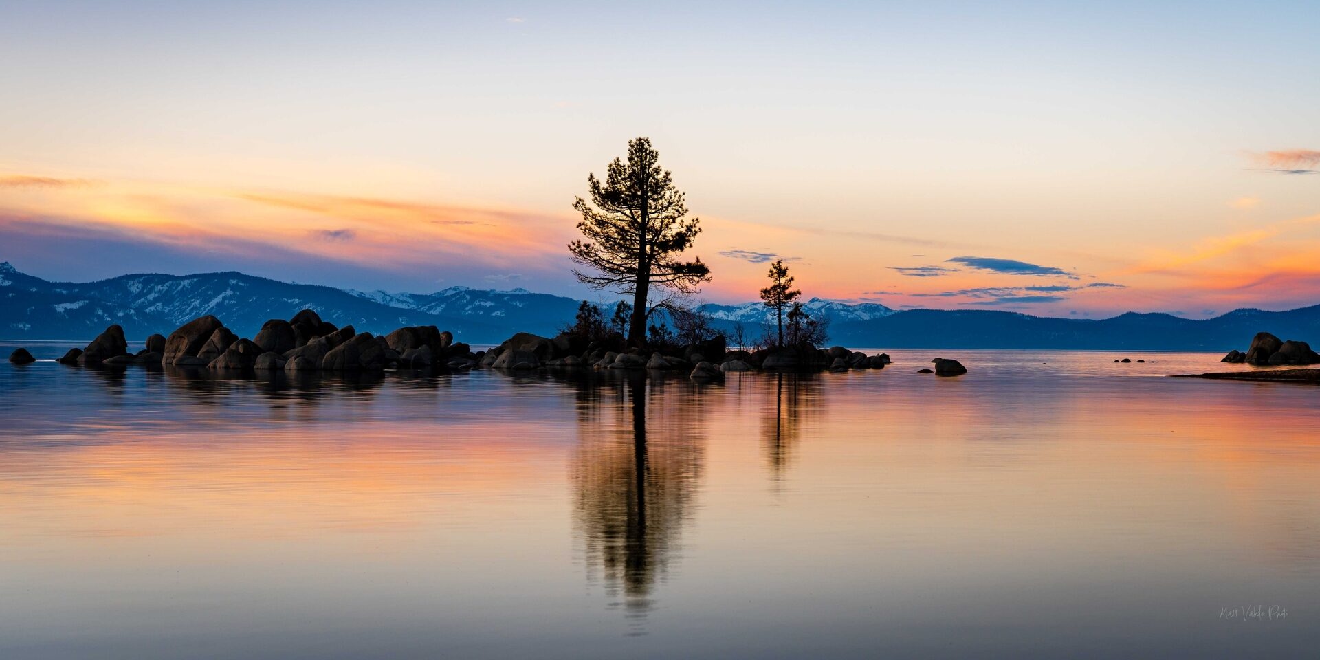 Lake Tahoe South - Zephyr Cove California stunning sunset with a lone tree in amongst rocks on the lake