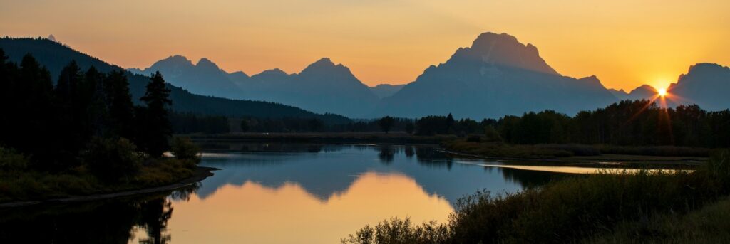 Jackson Wyoming Grand Tetons at sunset with the mountains and sunset reflecting in the lake