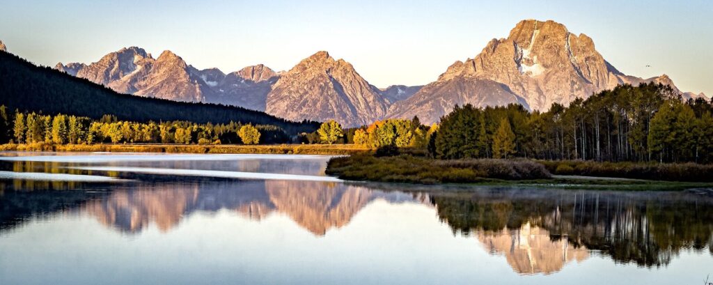 Grand Teton National Park Mountains stunning portrait photo of the Grand Tetons on a clear day with ultra still lake reflecting the mountains and scenery